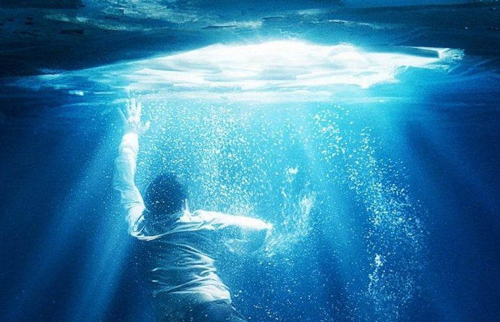 fragment plakatu na film przypływ wiary, chłopiec pod lodem, wyciągający rękę ku światłu